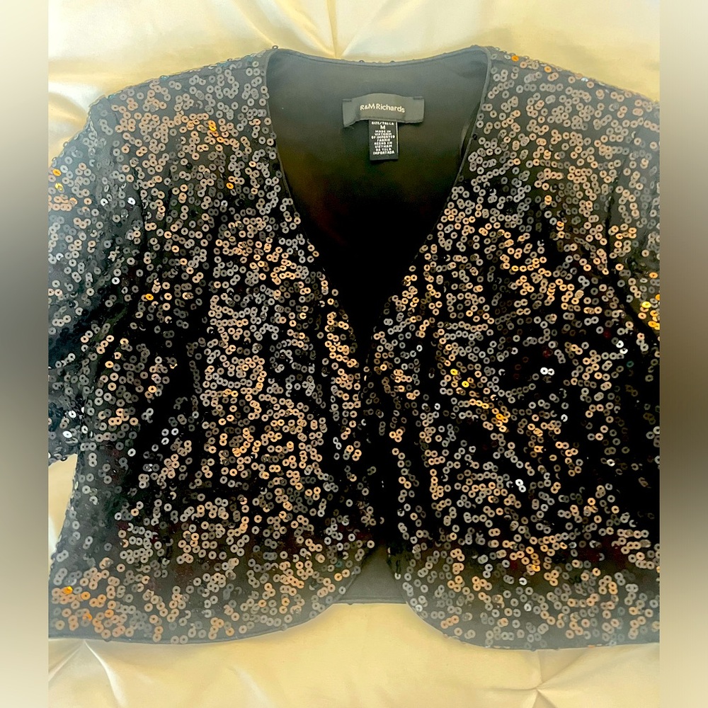 This is a stunning black cropped jacket adorned with sequins.
